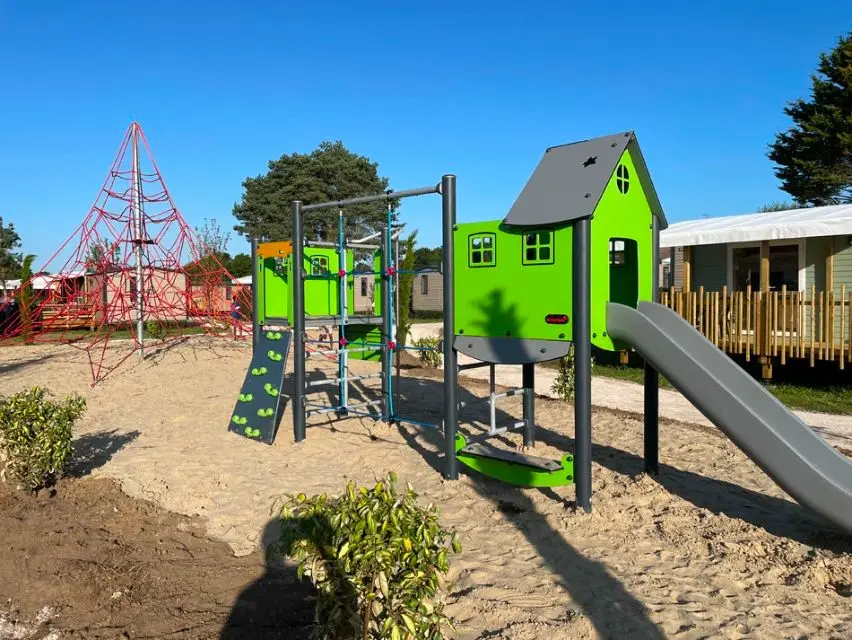 Terrain de jeux avec structure verte et toboggan.