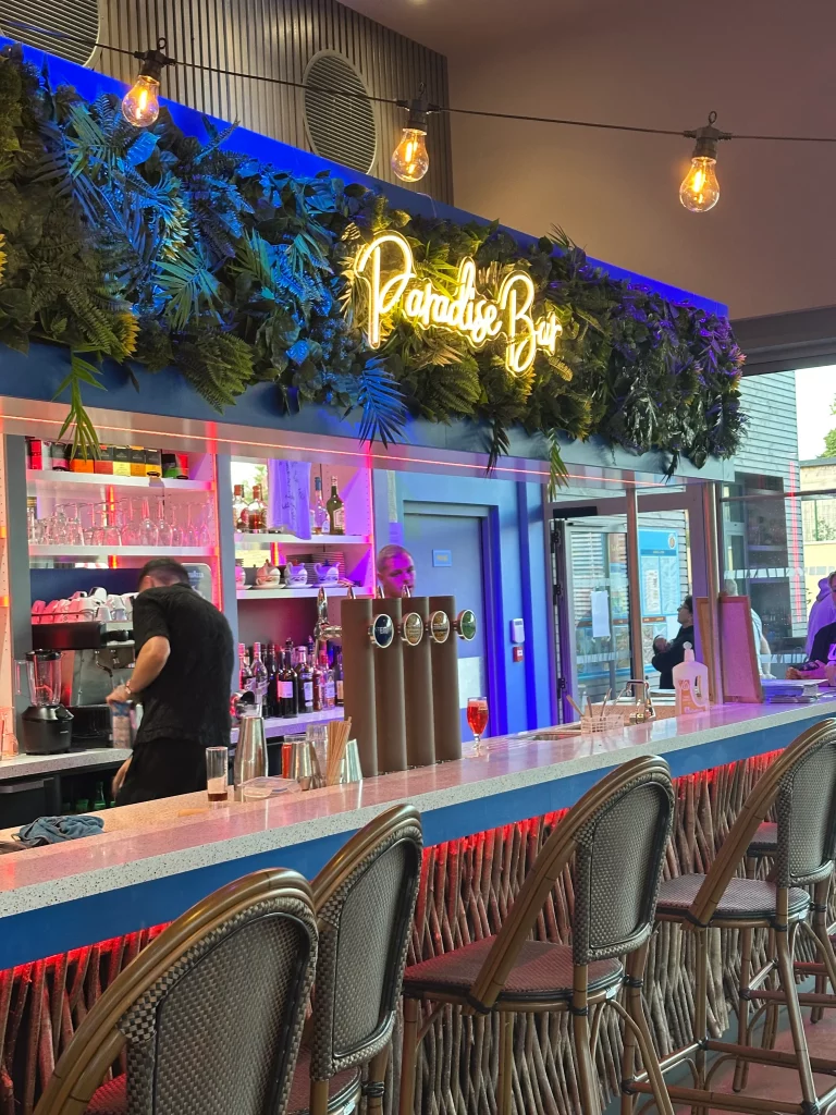 Bar lumineux avec décor tropical et personnes.