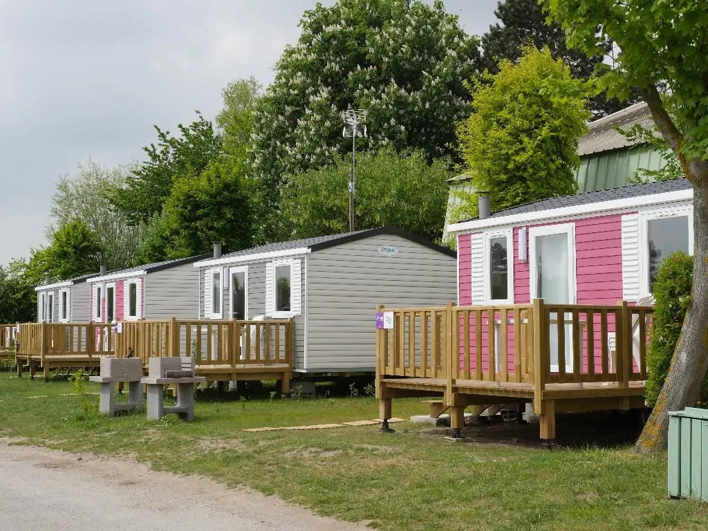 Mobil-homes colorés dans un camping verdoyant.