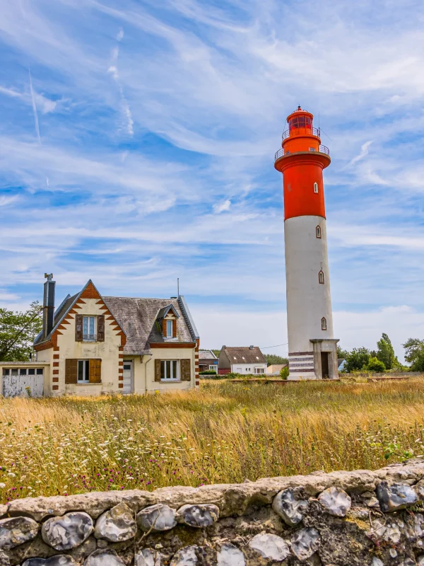 Maison et phare sous ciel bleu.