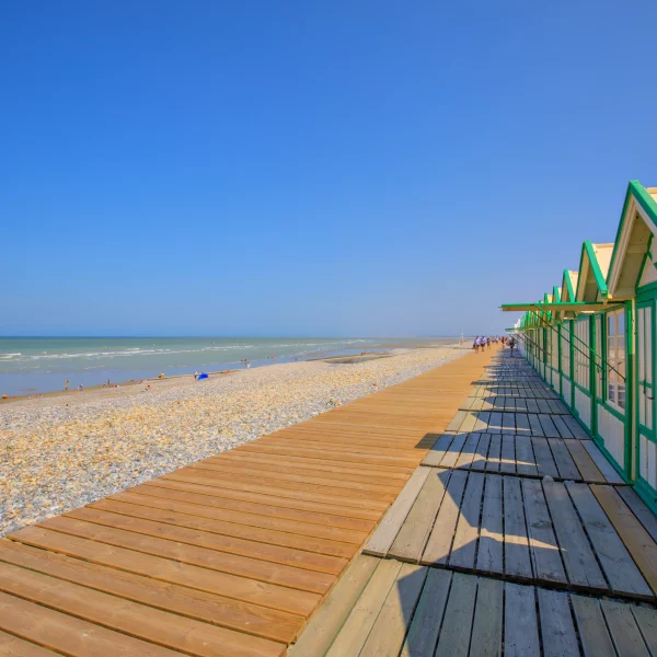 Plage avec cabanes en bois et galets.