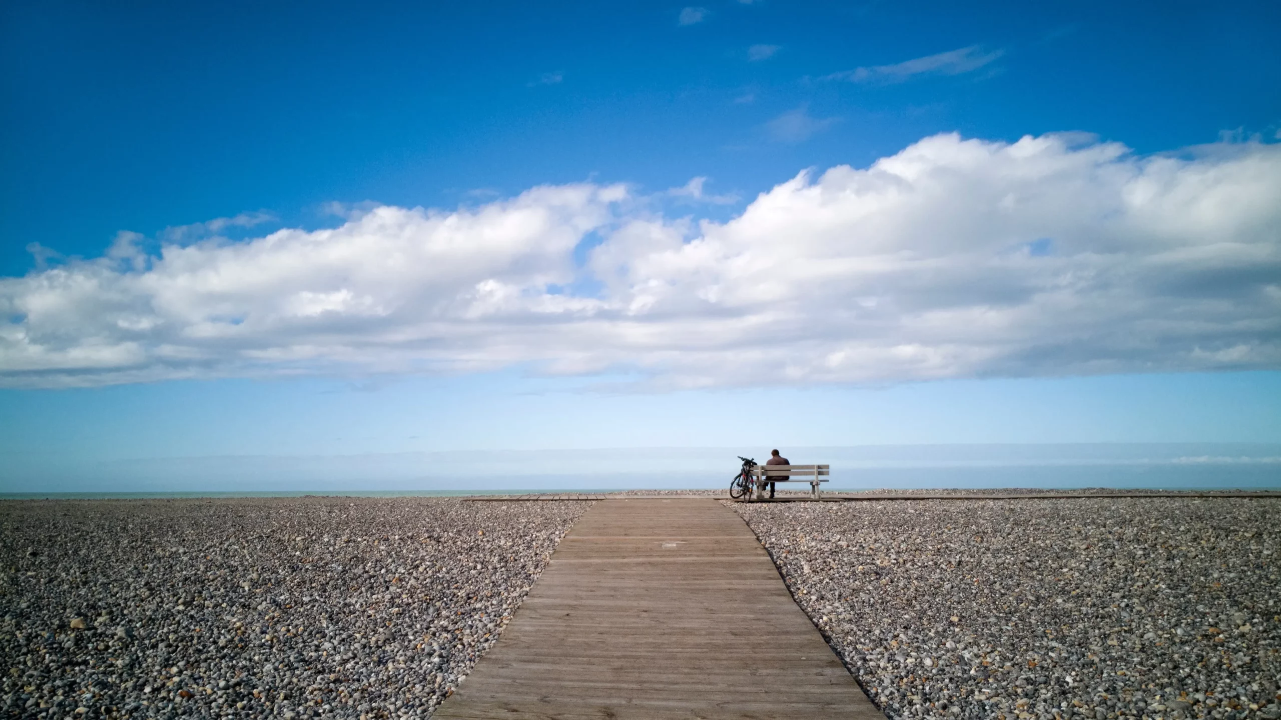 Personne assise sur un banc face à l'océan.