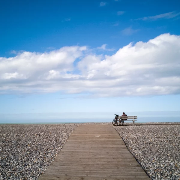 Personne assise sur un banc face à l'océan.