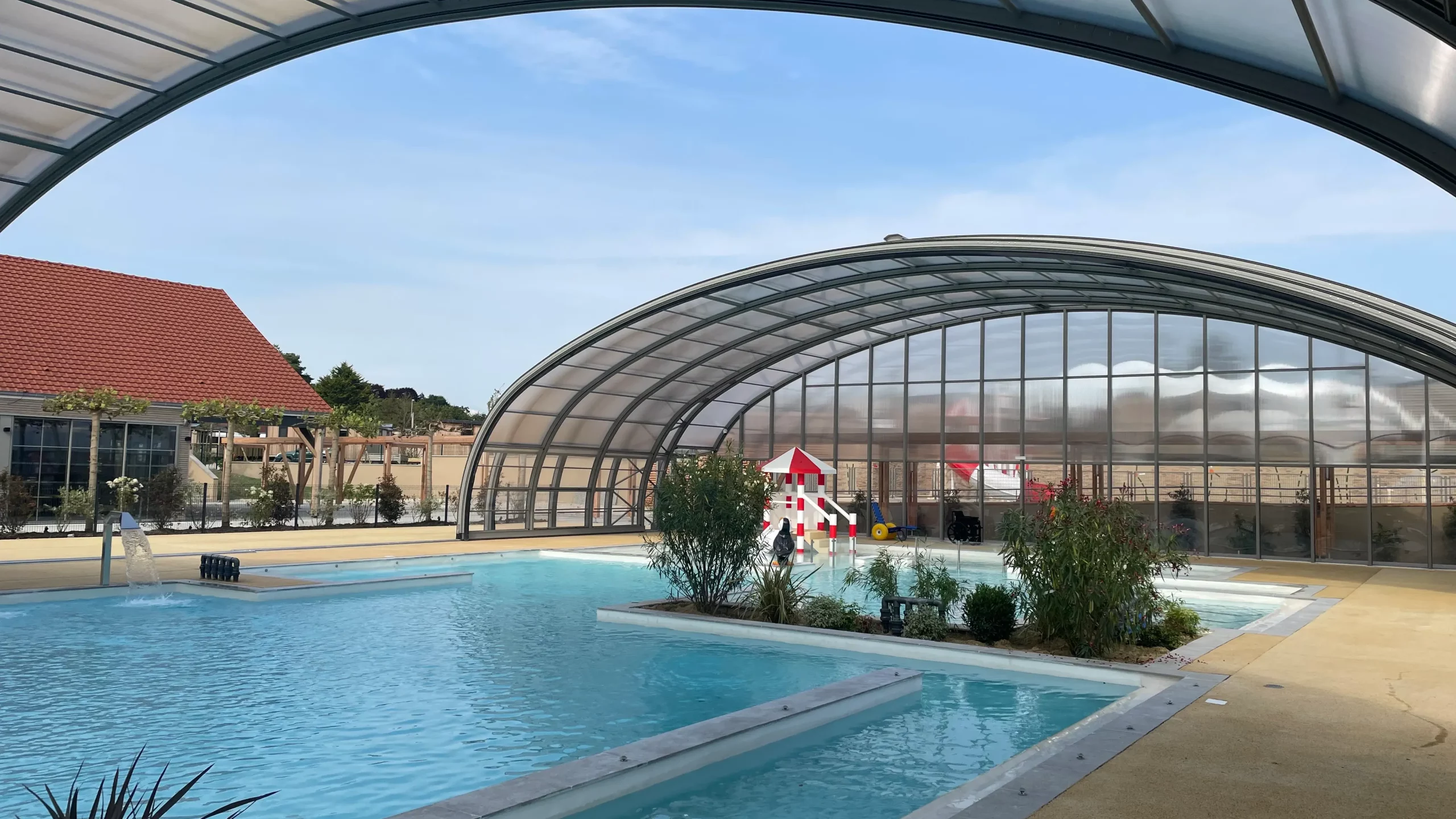 Piscine avec toit rétractable, aménagement extérieur moderne.