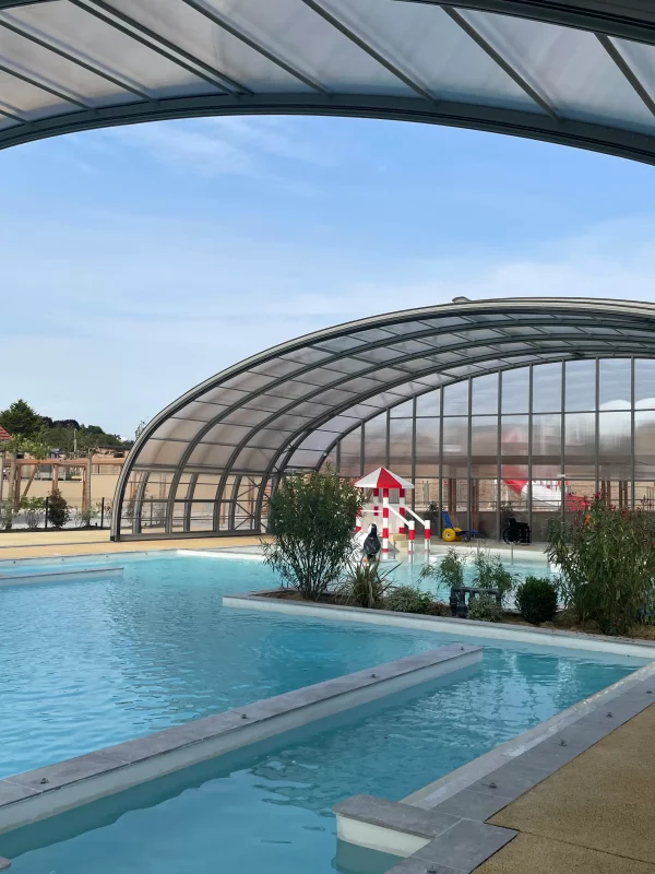 Piscine avec toit rétractable, aménagement extérieur moderne.