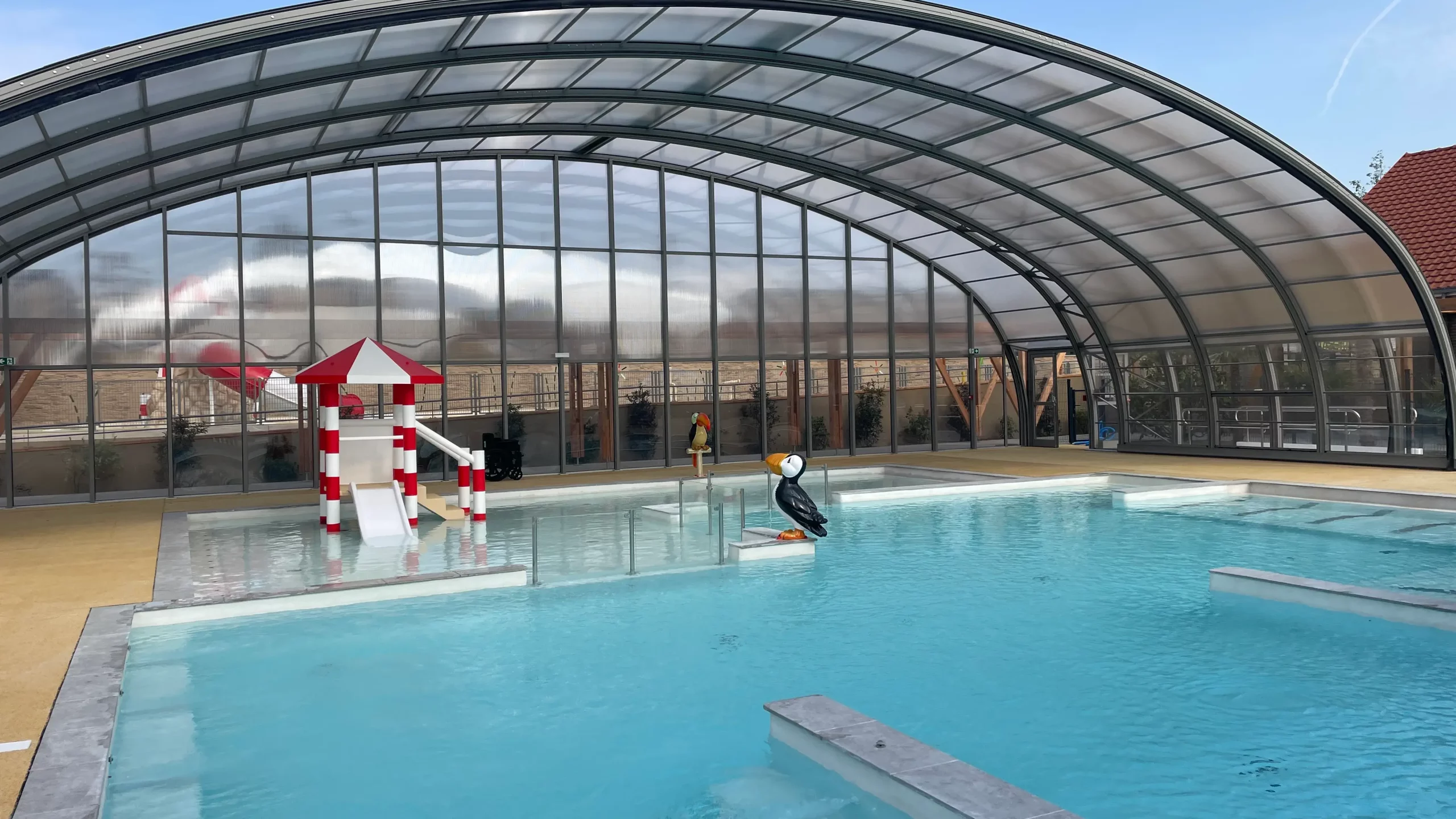 Piscine couverte avec jeux d'eau et toboggan.
