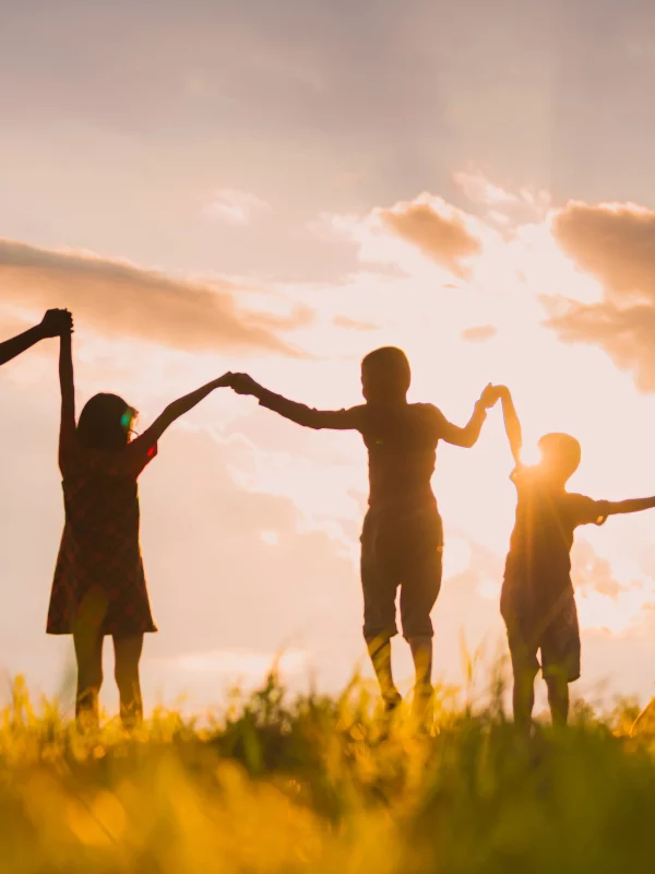 Enfants tenant les mains au coucher du soleil.