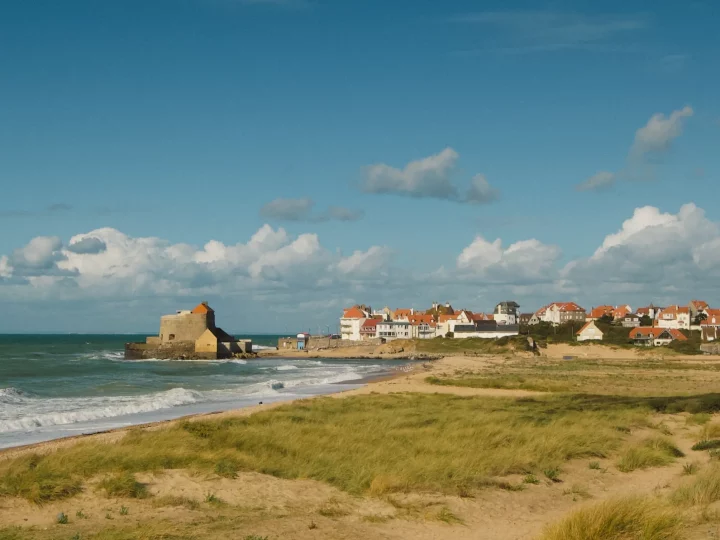 Plage et village côtier sous un ciel bleu.