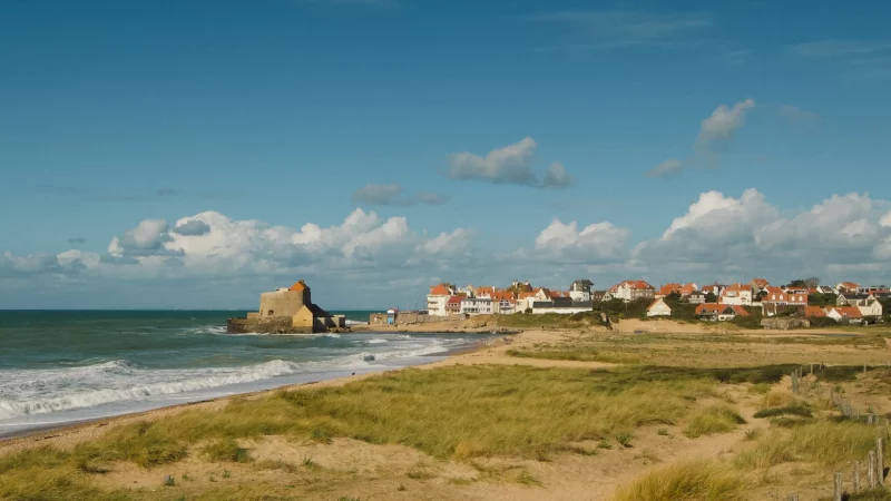 Plage et village côtier sous un ciel bleu.