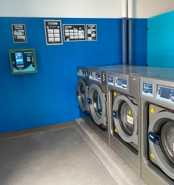 Laverie automatique avec machines alignées.
