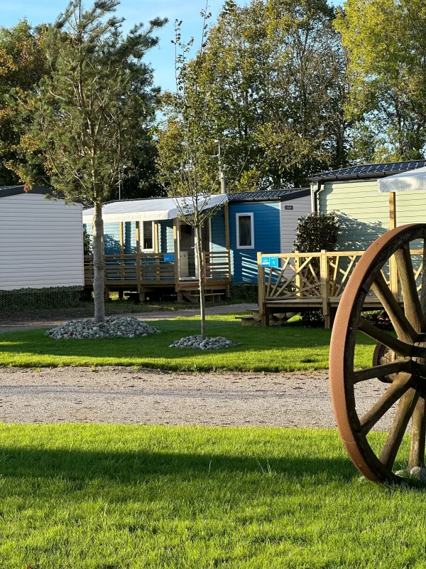 Mobil-homes ensoleillés dans un camping verdoyant.