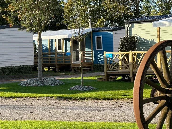 Mobil-homes ensoleillés dans un camping verdoyant.