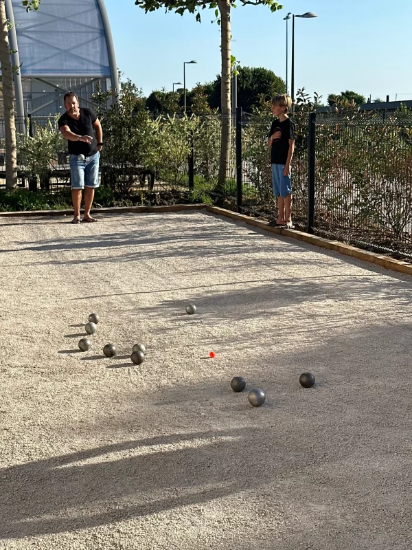 Personne jouant à la pétanque sur un terrain.