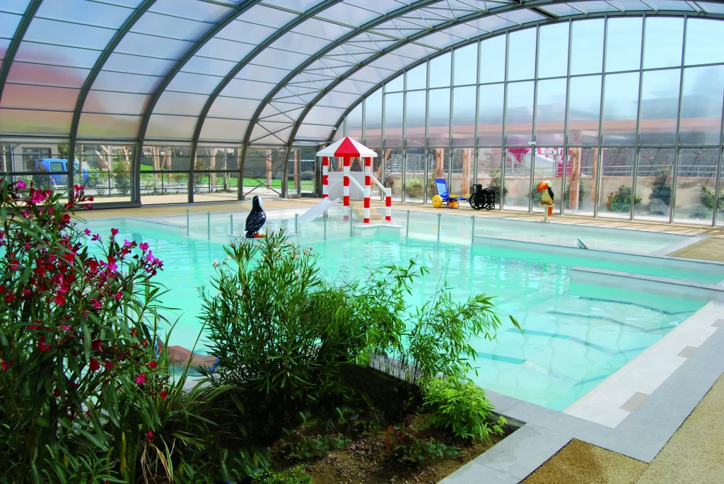 Piscine intérieure avec jardin et toboggan.