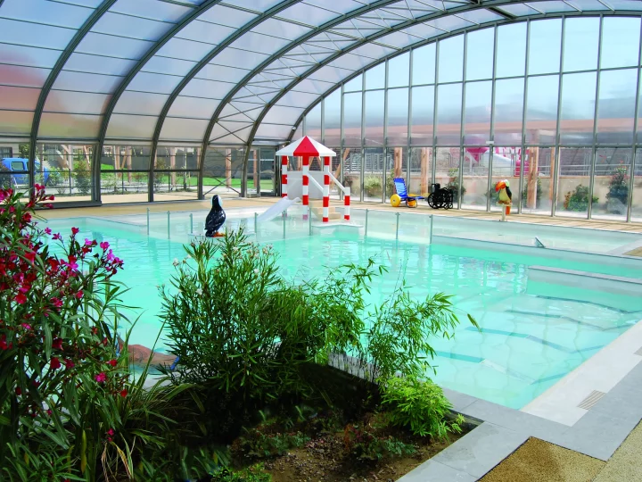Piscine intérieure avec jardin et toboggan.