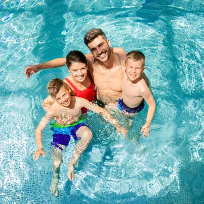 Famille heureuse nage dans une piscine claire.