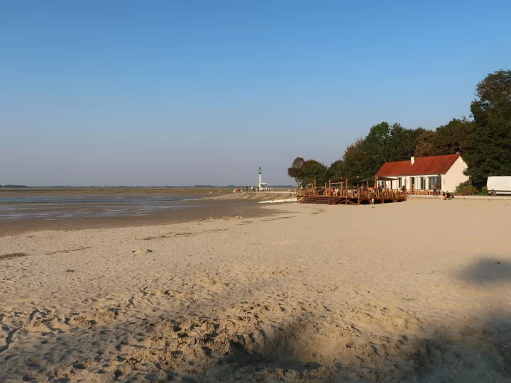 Plage avec chalet, dunes et phare.