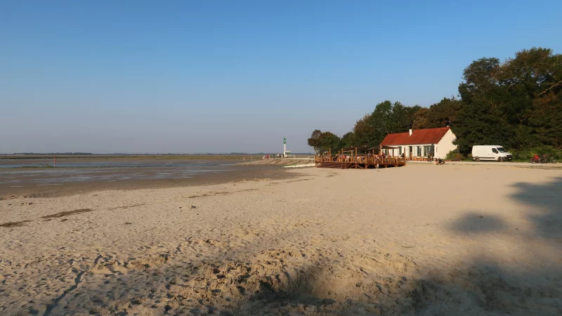 Plage avec chalet, dunes et phare.