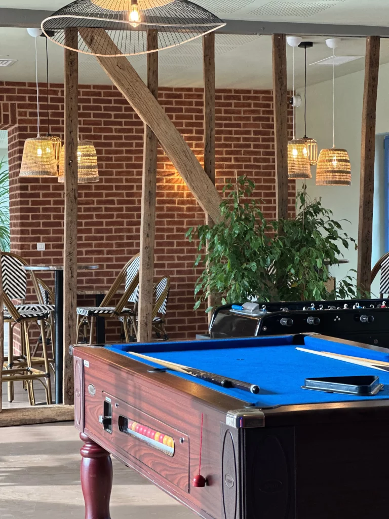 Intérieur avec table de billard et lumières suspendues.