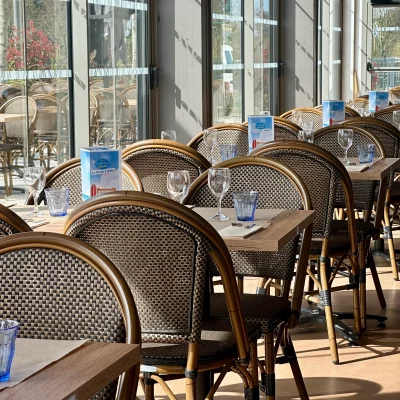 Salle de restaurant ensoleillée, tables vides.