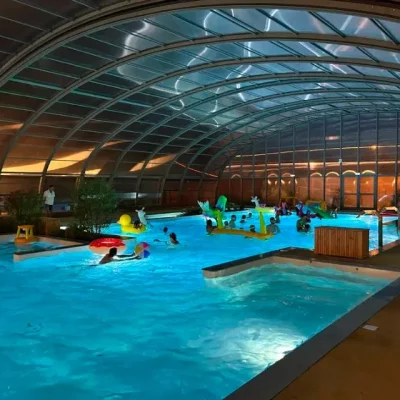 Piscine couverte avec des nageurs et jeux aquatiques.