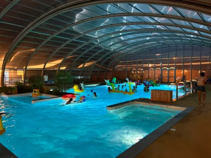 Piscine couverte avec des nageurs et jeux aquatiques.