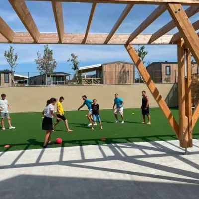 Personnes jouant au foot sur le terrain ensoleillé.