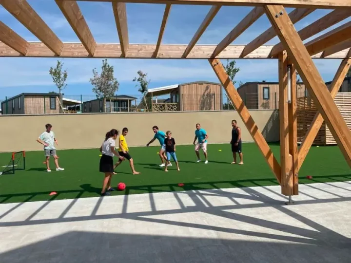 Personnes jouant au foot sur le terrain ensoleillé.