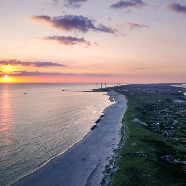 Coucher de soleil sur plage et village côtier.