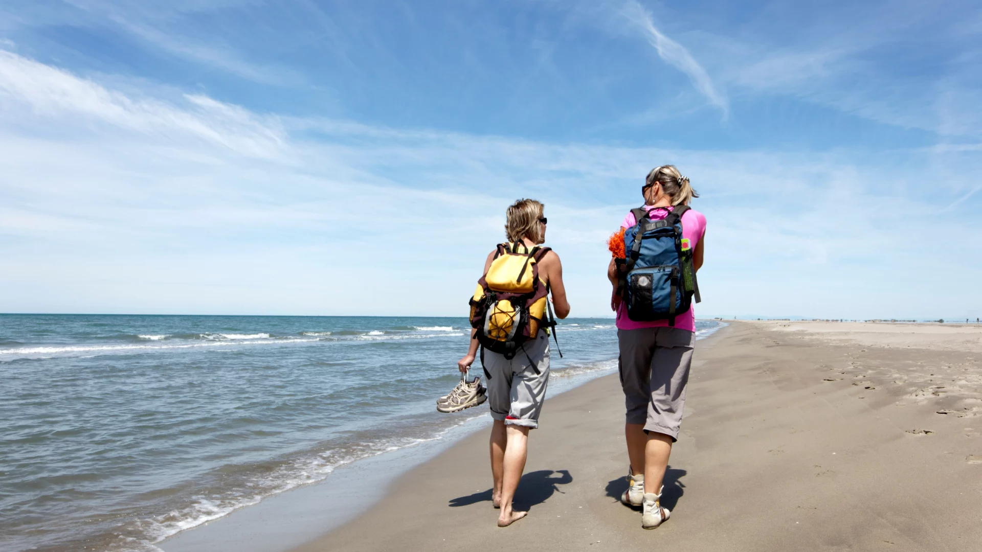 Deux randonneuses sur une plage ensoleillée.